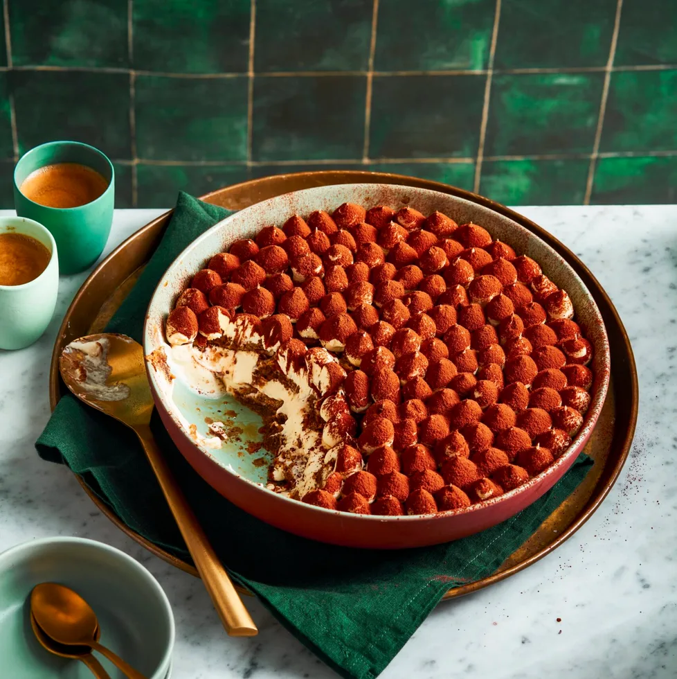 traditional tiramisu recipe with piped meringue topping and cocoa powder on top