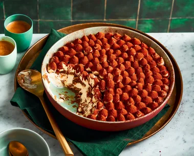 traditional tiramisu recipe with piped meringue topping and cocoa powder on top