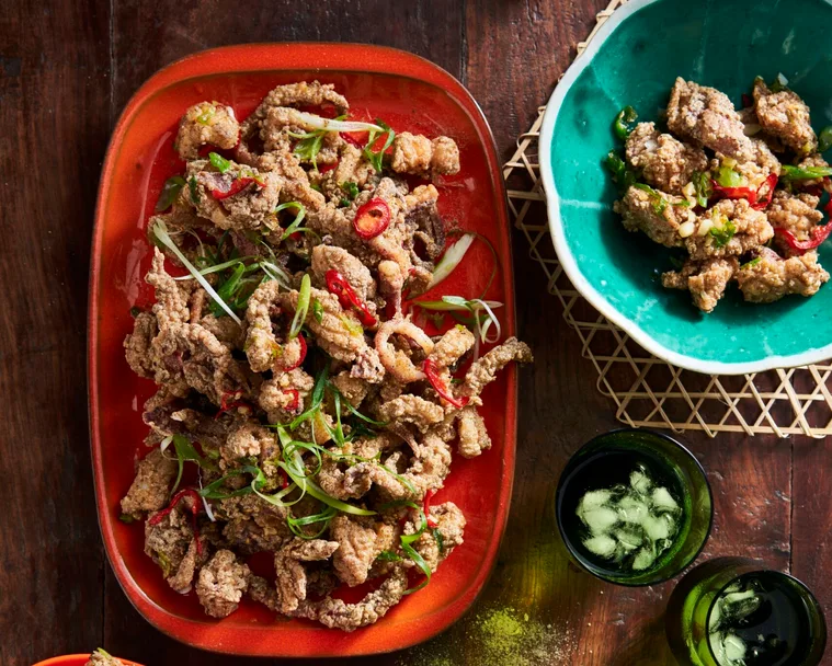 szechuan salt and pepper squid on oval red platter with additional herbs and lemon on the side