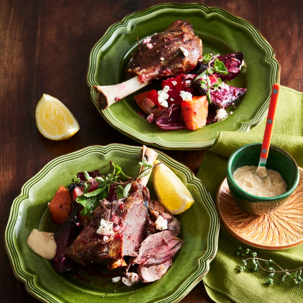 lamb shanks with beetroot and lemon wedges on bright green plate