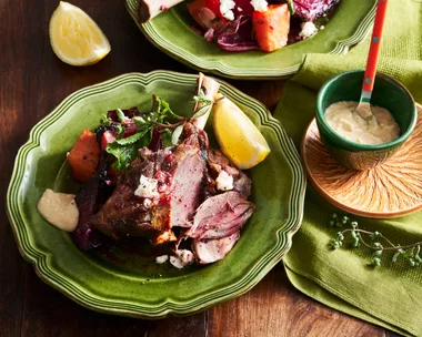 lamb shanks with beetroot and lemon wedges on bright green plate