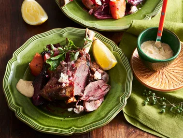 lamb shanks with beetroot and lemon wedges on bright green plate