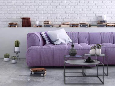 purple couch with cushions on it with white painted brick wall behind it