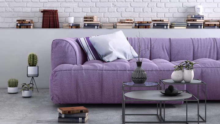 purple couch with cushions on it with white painted brick wall behind it