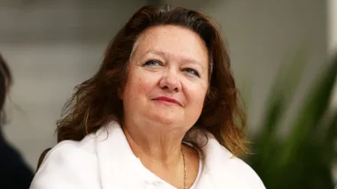 A woman with long brown hair wearing a white coat, gazing thoughtfully.