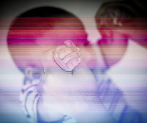 A baby's hand grasping an adult's finger, image is overlaid with horizontal color bars, suggesting a distorted or glitched effect.