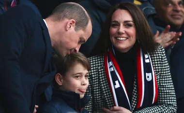 Family smiling and interacting at a public event, with a woman wearing a checkered coat and scarf.