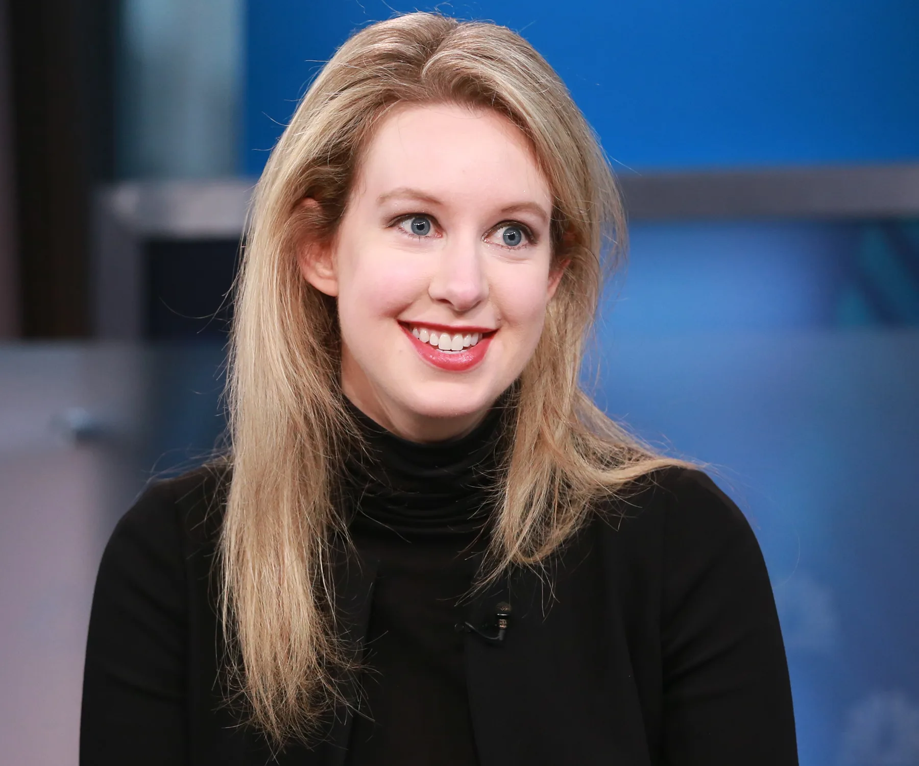 Elizabeth Holmes dressed in what would become her signature CEO-look: Bold red lip, black turtleneck and black pants.