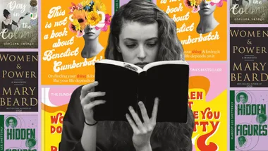 A woman reading a book surrounded by covers of books celebrating women's achievements.