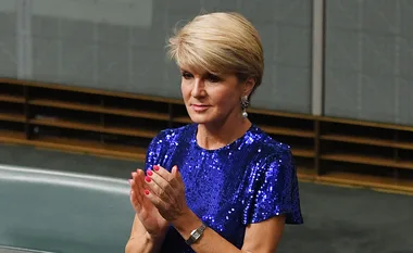 A woman in a blue sequin dress clapping her hands in a formal setting.