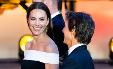 Two people smiling in formal attire at a cinematic event, possibly related to "Top Gun".