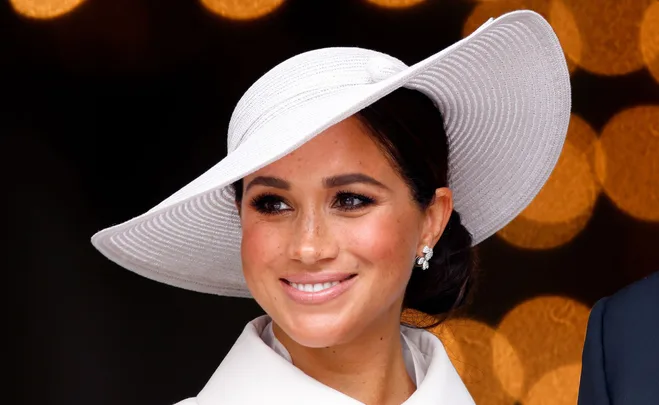 Smiling woman in a white hat with bokeh background.