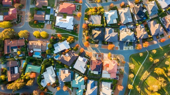 Aerial view of a suburban neighborhood with houses, trees, and winding roads.