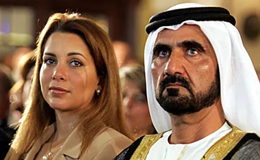 A man in traditional Middle Eastern attire beside a woman with long hair in formal clothing, both looking forward.