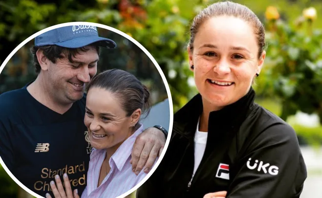 "Ash Barty smiling, with a man in a casual shirt, outdoors with greenery in the background."
