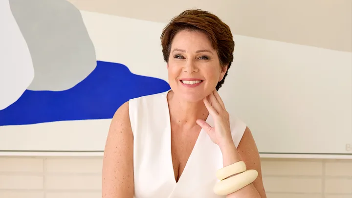 Smiling woman in white dress with art background.