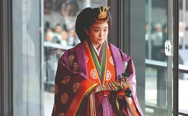 A woman wearing traditional Japanese attire during a formal event, adorned in a colorful kimono with elaborate hairstyle and headpiece.