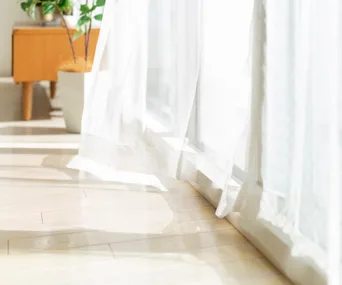 light coloured floor by white curtain with sunlight coming through