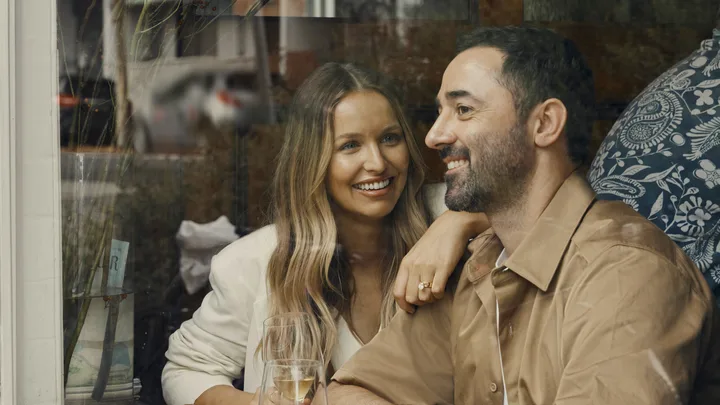 Smiling couple enjoying a drink together indoors by a window.