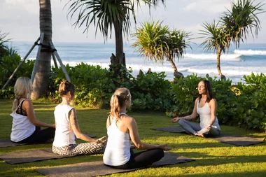 4 women meditating on yoga mats by the beach in Bali