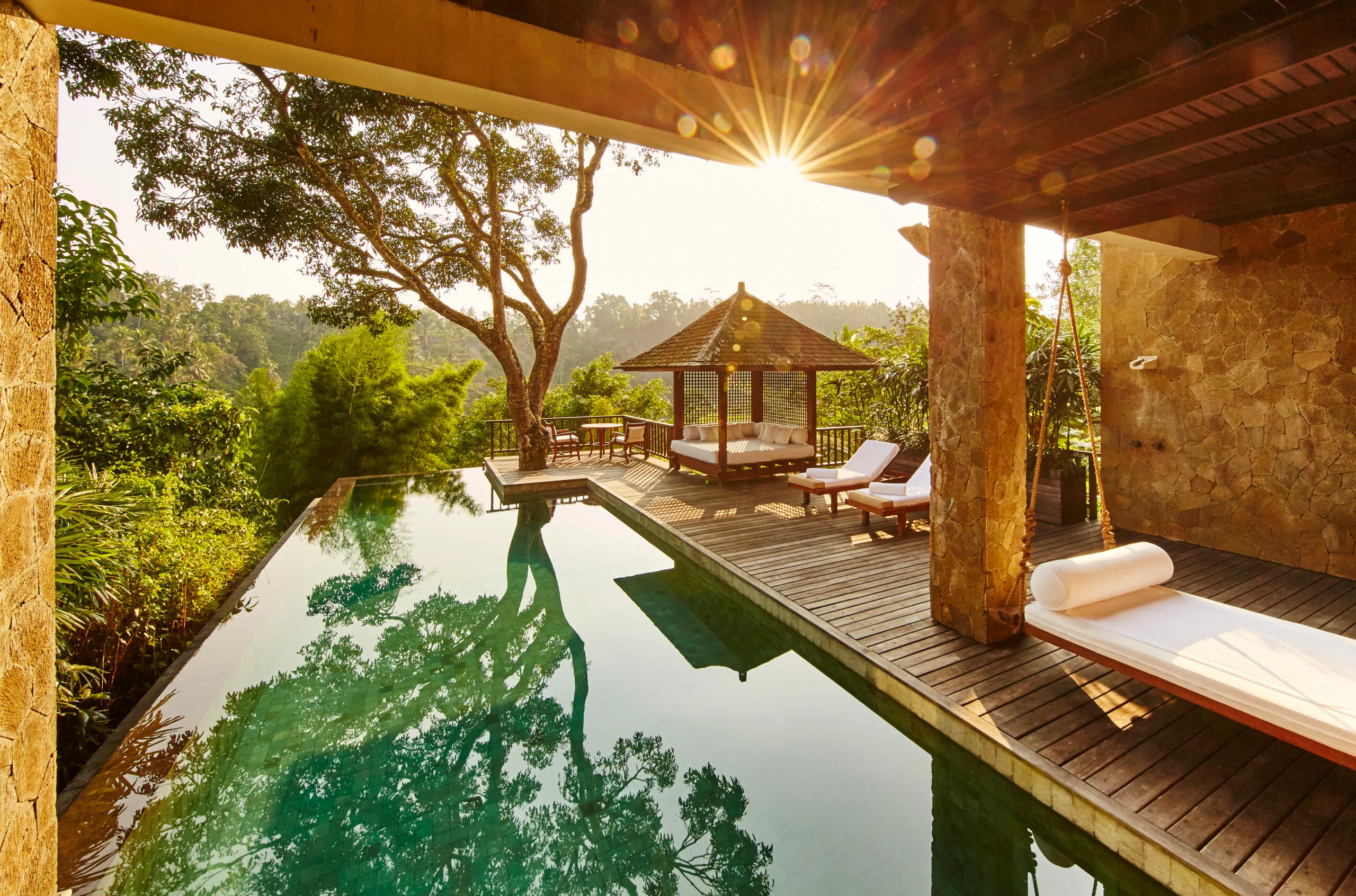 View of an outdoor pool and deck in a villa in Como Shambhala resort in Bali