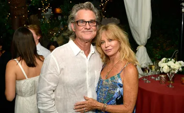 Happy couple embracing at an elegant outdoor event with twinkling lights and flowers in the background.