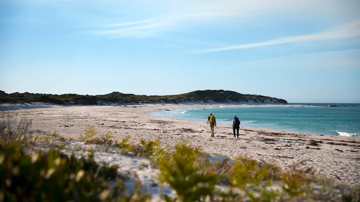 2 people walking on a beach in Tasmania as part of the wukalina Walk hike
