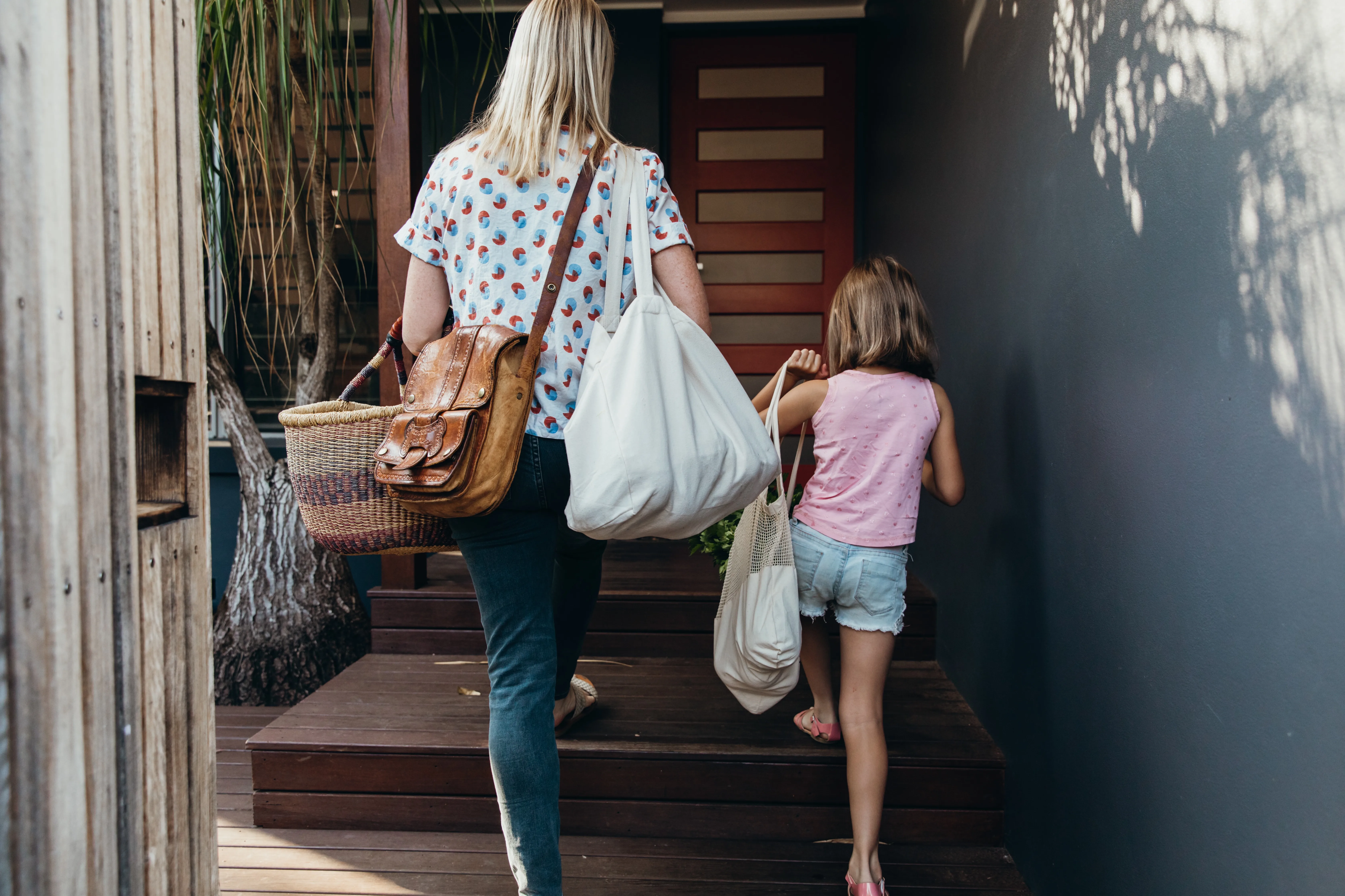 Real life young Australian mum and daughter bring in their groceries in eco shopping bags and basket