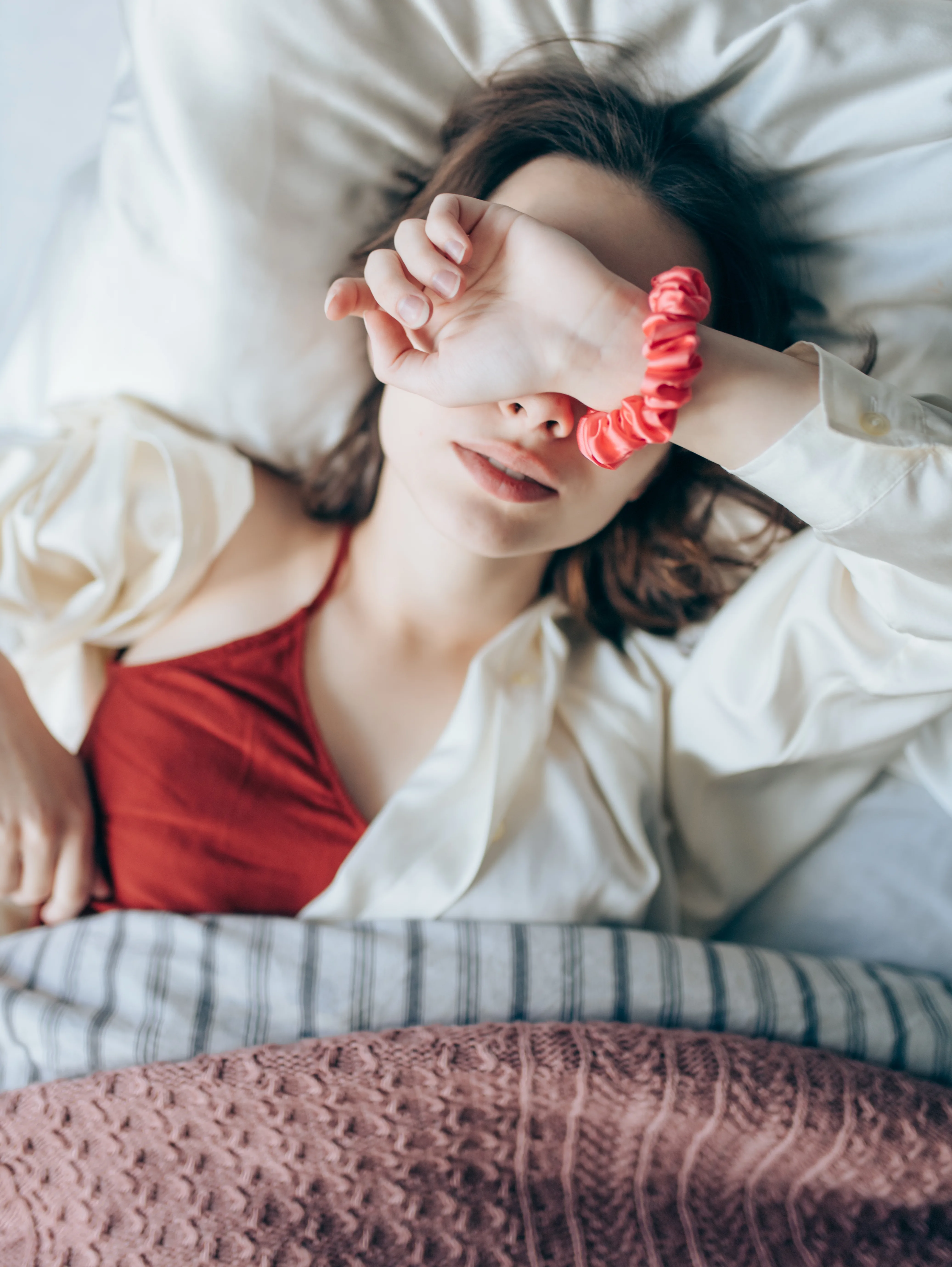 woman in bed with hand over her eyes