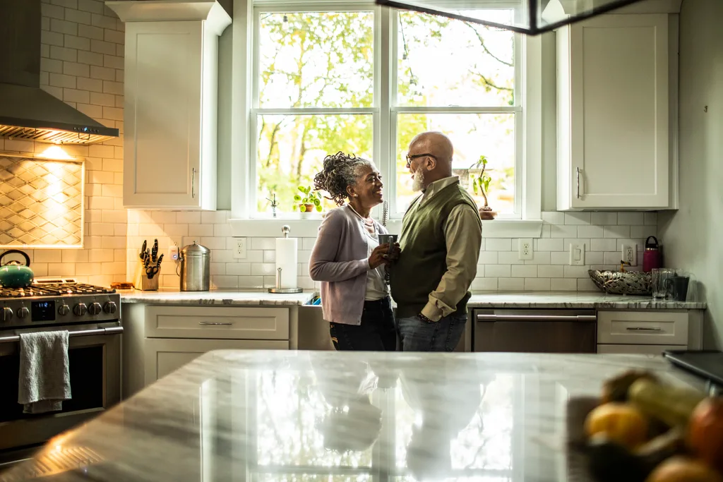 Senior couple embracing in kitchen of suburban home.