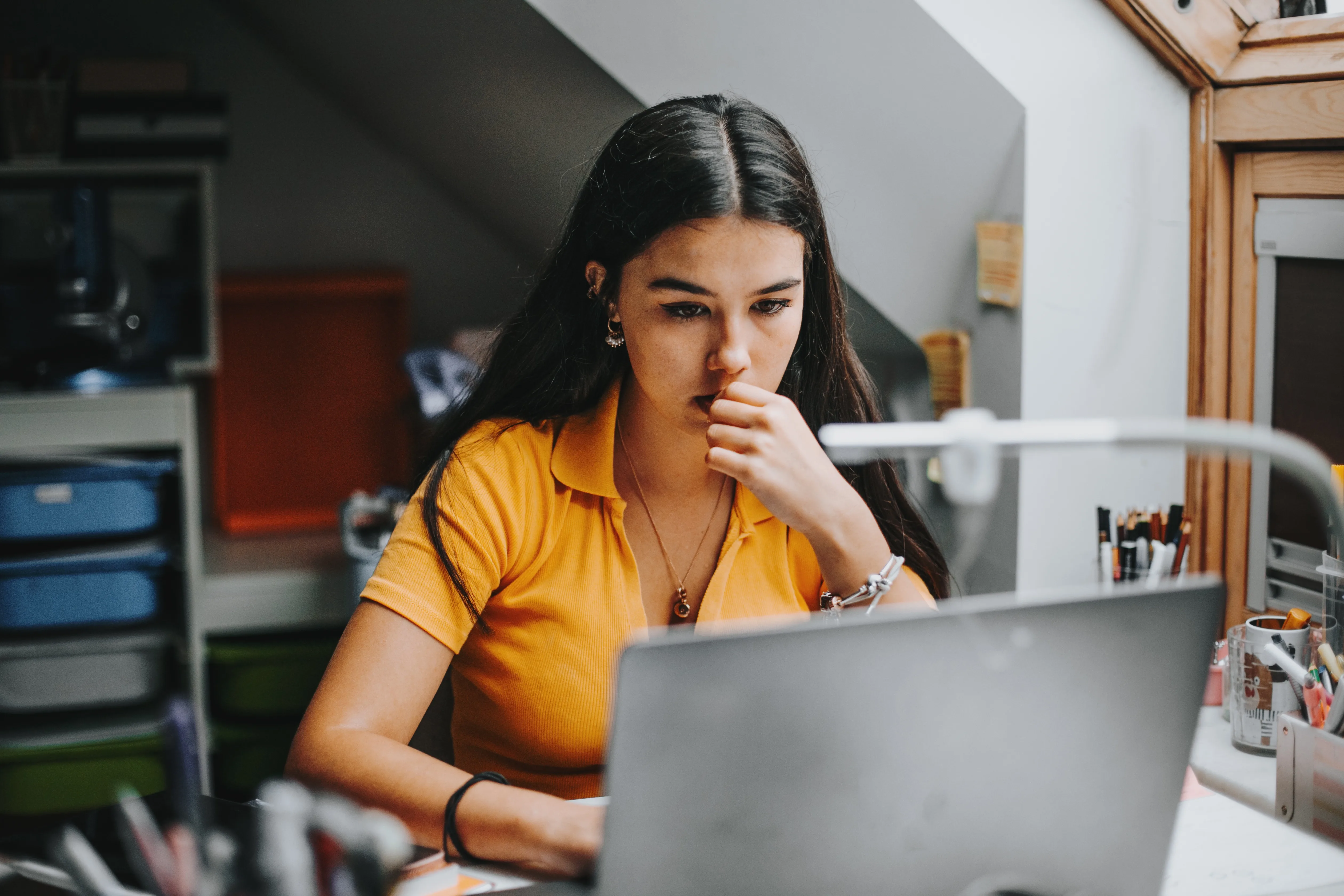 A university student works on assignment in her dorm room.She is smiling and in the background there is a big blackboard