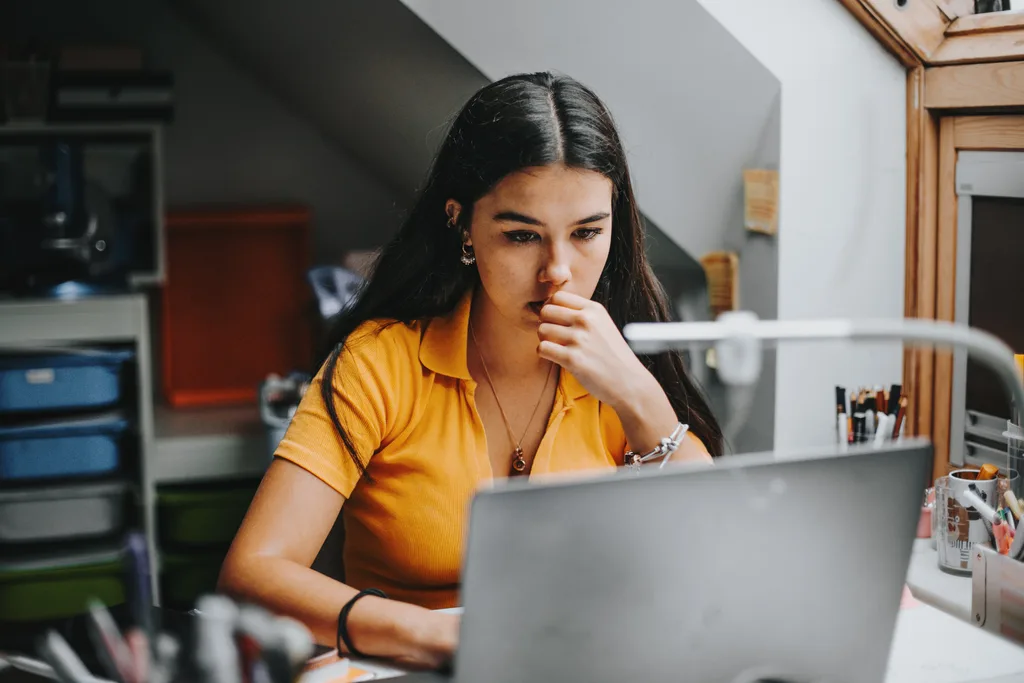 A university student works on assignment in her dorm room.She is smiling and in the background there is a big blackboard