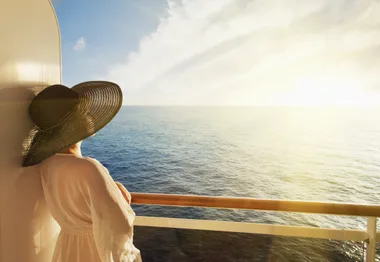 Woman in sun hat looking out to sea on a cruise ship