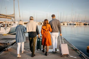 Reav view of group of mature friends walking on pier, arriving to yacht