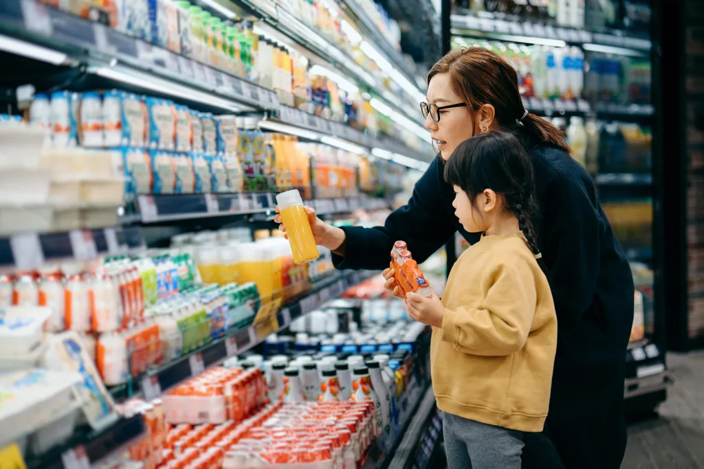 Mother and child selecting drinks in a supermarket aisle.