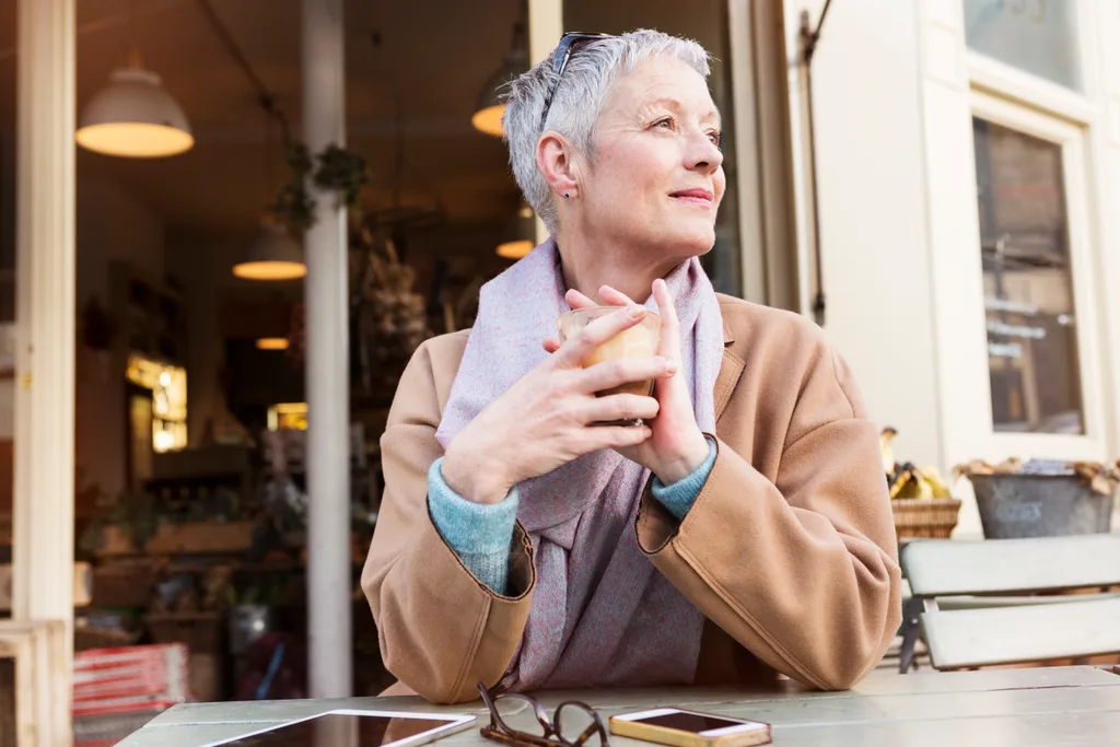 woman with short grey hair drinking a latte.