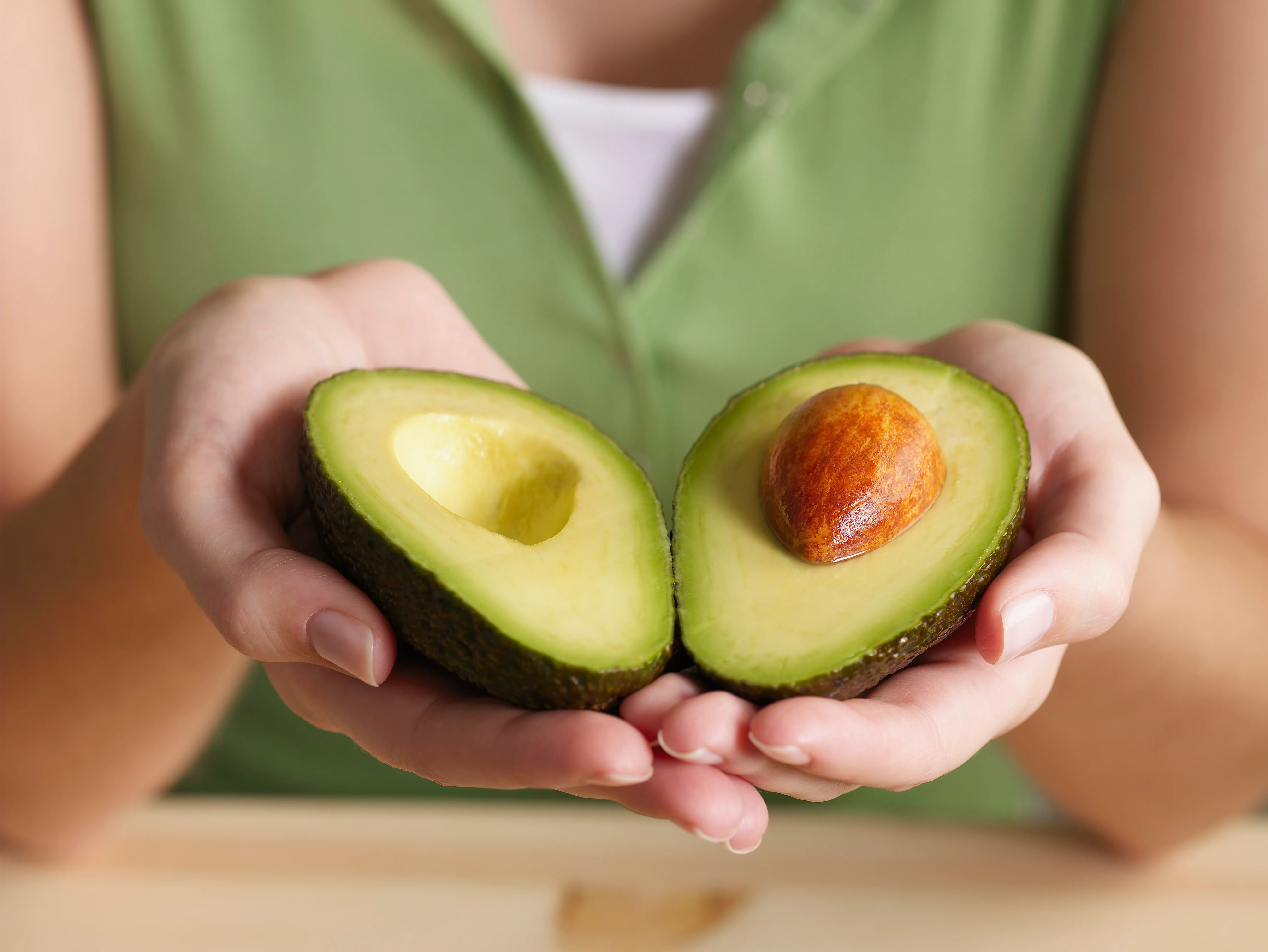female hands holding avocado.