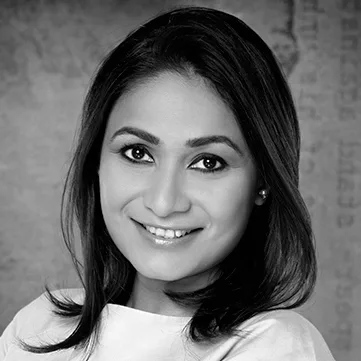 Portrait of a smiling woman with shoulder-length dark hair against a textured background in black and white.