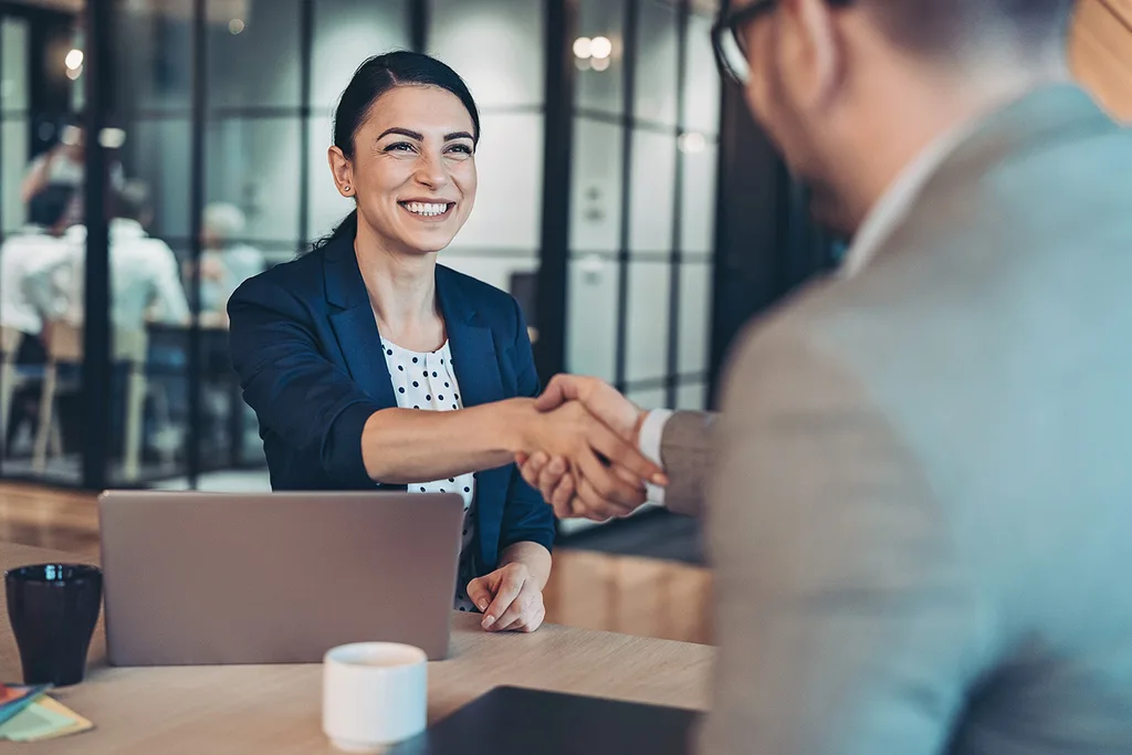 A woman shakes hands with a colleague. 