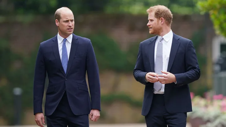 Two men in suits walking outdoors, engaged in conversation.