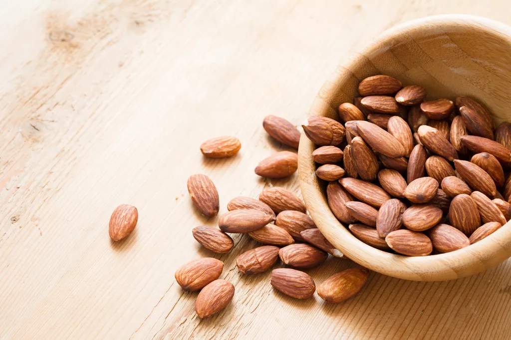 Almonds in wooden bowl on wooden table background