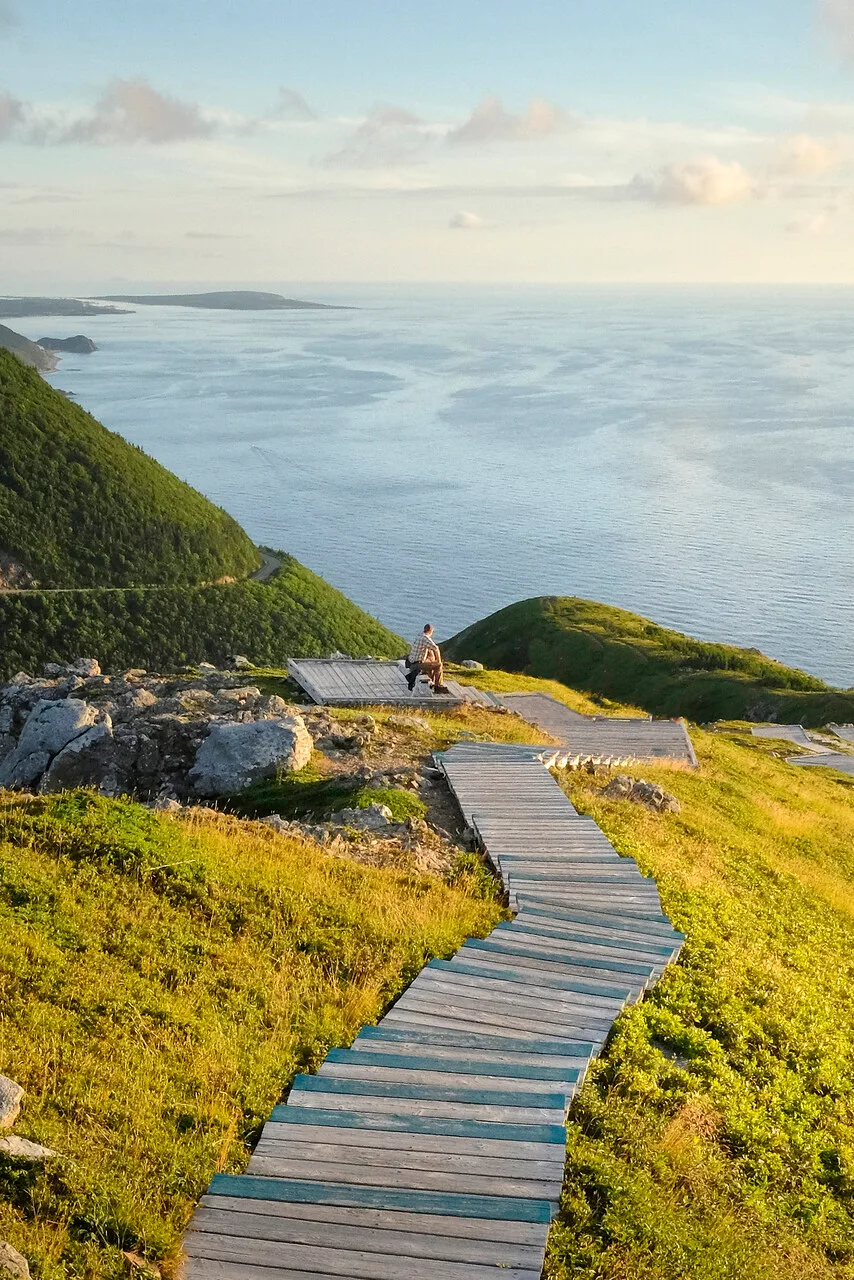 man sitting on hill looking out at the ocean