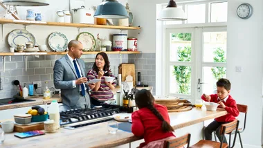 Family of four in kitchen discussing budgeting