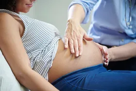 A healthcare provider examining a pregnant woman's belly, indicating a prenatal check-up.