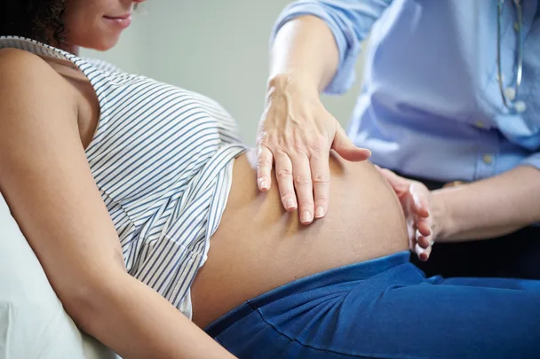 A healthcare provider examining a pregnant woman's belly, indicating a prenatal check-up.