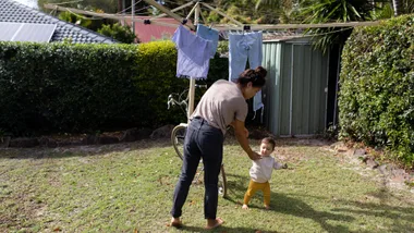 Woman with young child hanging out laundry to represent housing future fund helping homeless women