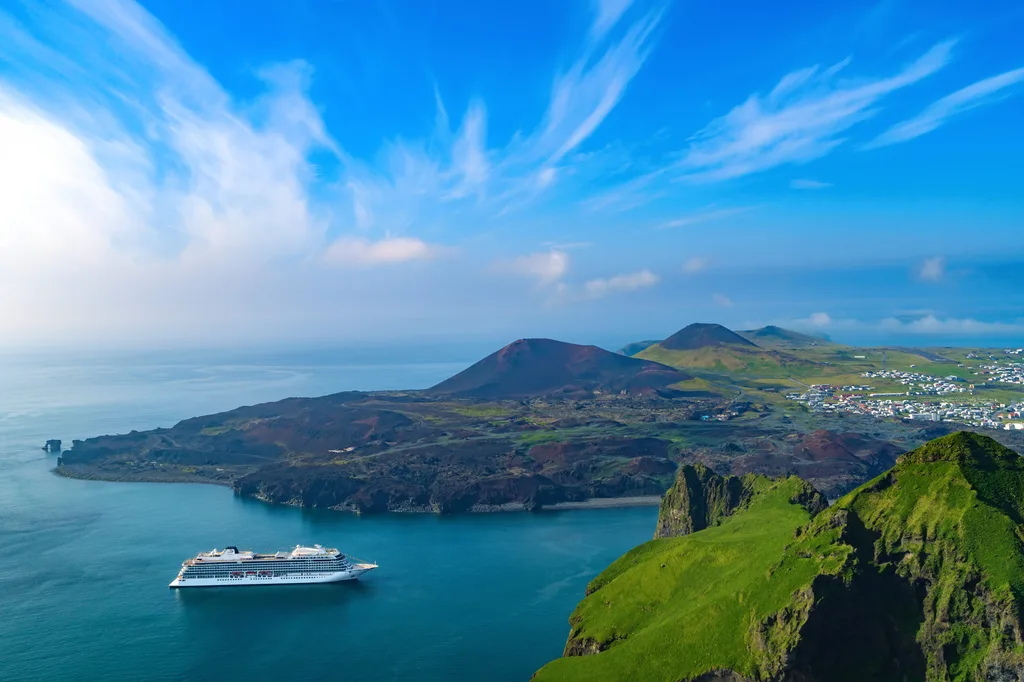 Viking Sky off-shore to the coastal town of Heimaey, Iceland. It is the largest island in the Vestmannaeyjar archipelago or Westman Islands. Along the coast is Eldfell volcanic cone.