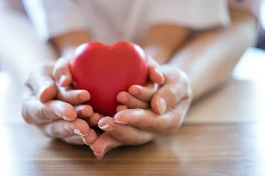 Woman and child cupping a red heart shape in their hands