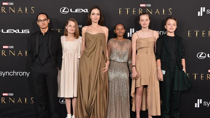 Group of individuals in formal attire on the red carpet for a Marvel Studios "Eternals" event.