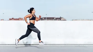 Woman in athletic gear running outdoors on a clear day.